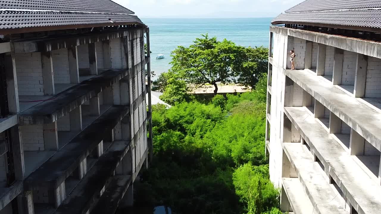 Drone percorre um hotel abandonado para revelar uma praia deslumbrante com praticantes de jet ski.