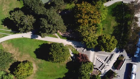 3-4 modern futuristic circlular shaped park birds eye view aerial rise over empty dry water fountain pool across restricted childrens park during covid-19 pandemic social distancing city bus hub paths