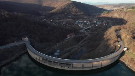 Luftaufnahme-Des-Damms,-Der-Das-Wasserreservoir-Von-Der-Kleinen-Stadt-Im-Tal-Zurückhält