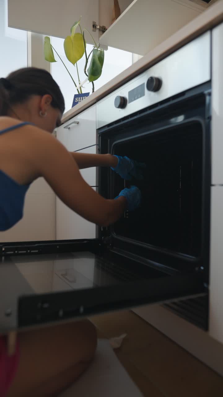 Donna che pulisce il forno della cucina