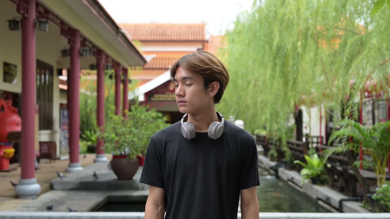 Young Thai Asian man in traditional Asian Zen garden during summer. Confident, relaxed, and authentic look suitable for various concepts and uses