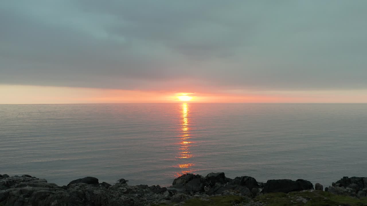 Tidevandspøl nær Farstadsanden stenstrand ved solnedgang i Norge, drone-dolly til det sidste lysskær under skyerne.