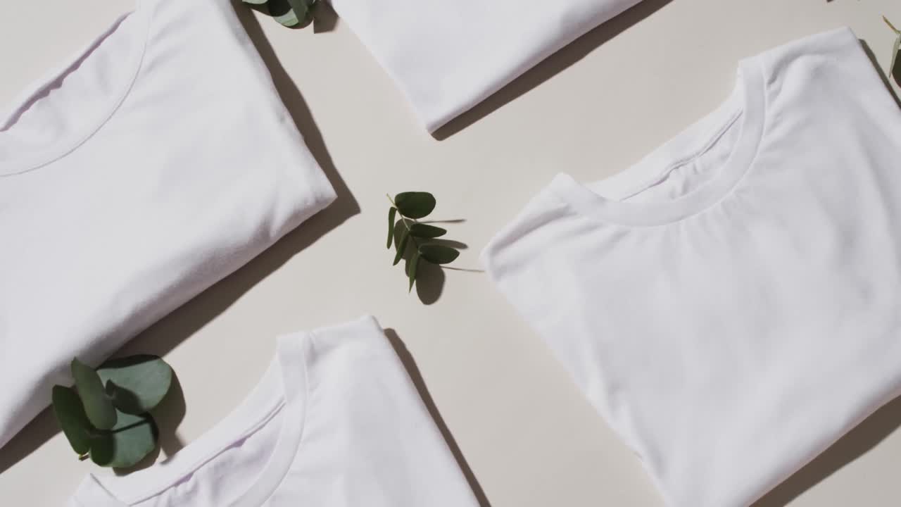 Video of flat lay of folded white t shirts with copy space on white background