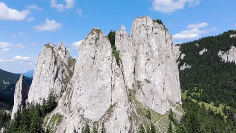 close up view of jagged and barren mountain of the lonely rock with evergreen forest in romania