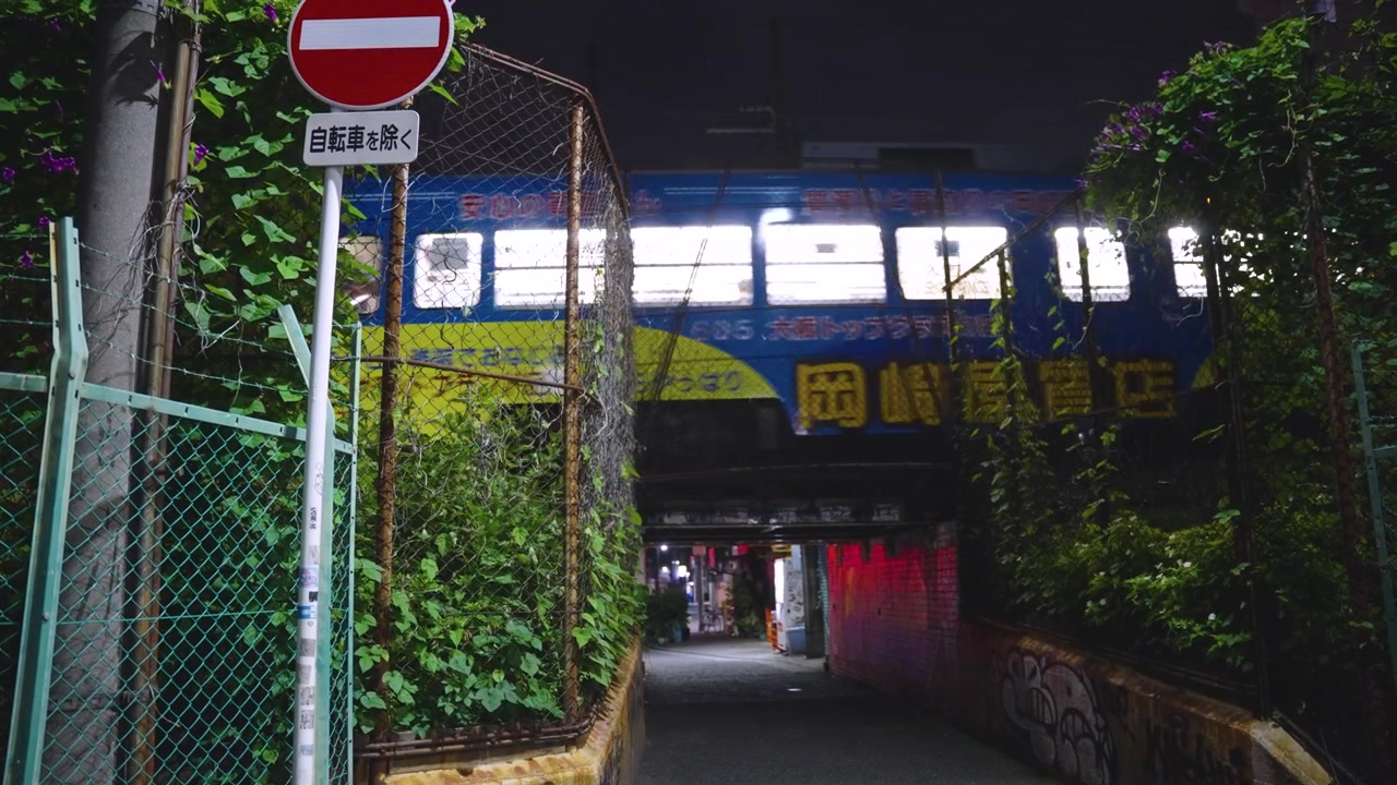 Hankai sporvogn passerer Nishinari-distriktet i Osaka om natten, slumområde i Japan.