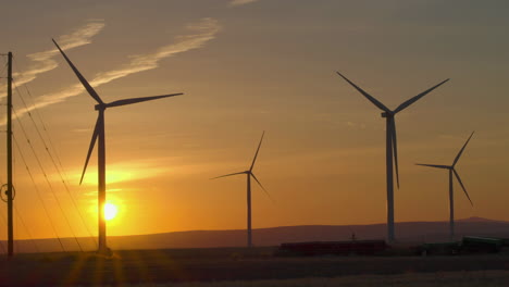 silhouette of wind turbines at wind farm spinning against the sunset sky in oregon, usa. - wide shot