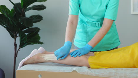 the girl talks on the phone and smiles during hair removal on her legs. shugaring master removes hair from legs