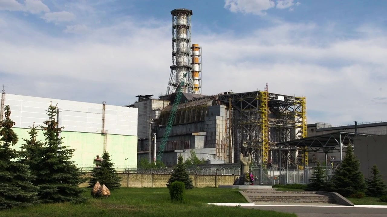 La cámara se desplaza por los terrenos mostrando el antiguo sarcófago de Chernóbil
