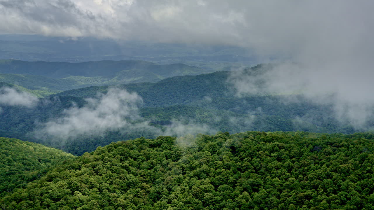 Misty rainfall fills the scene as the drone scans the mountain landscape