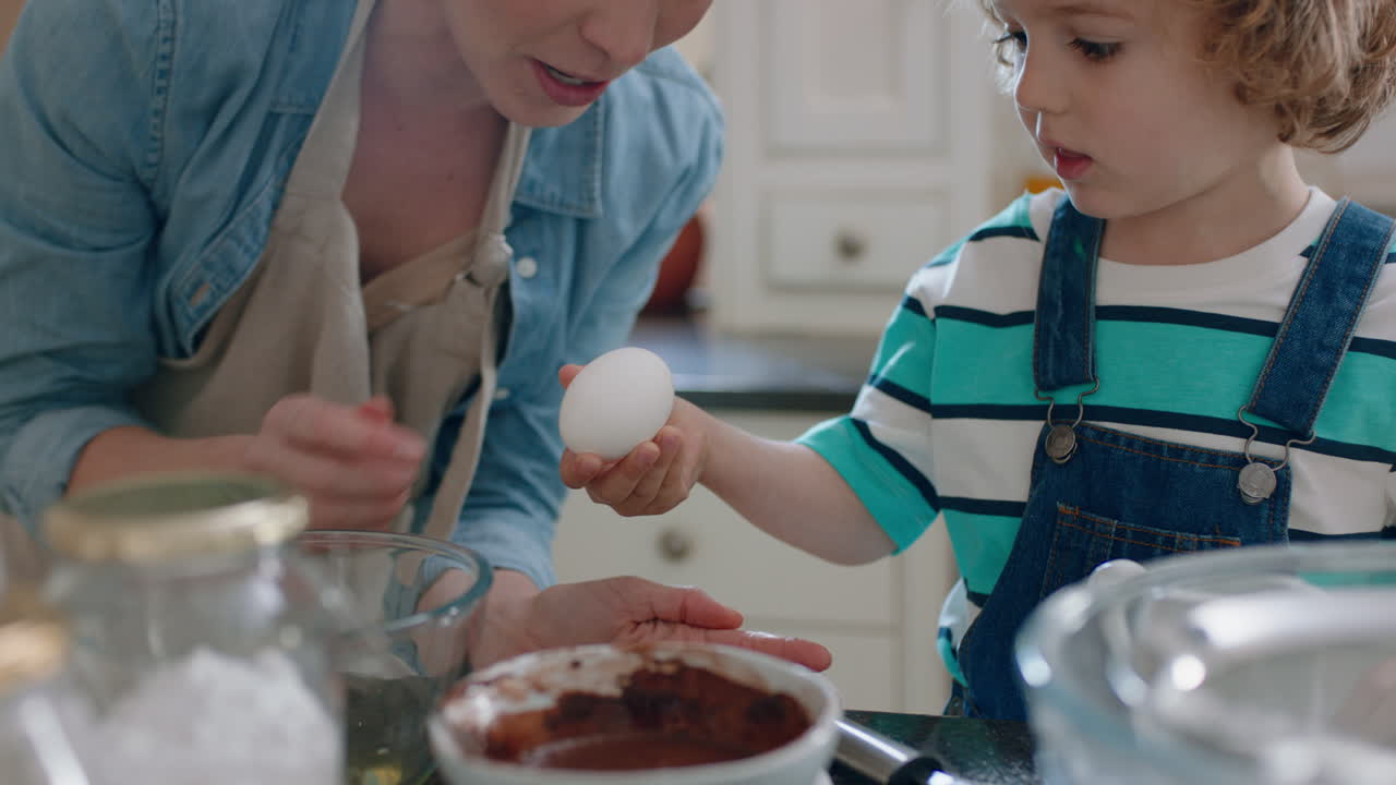 little boy helping mother bake in kitchen mixing ingredients baking choclate cupcakes preparing recipe at home