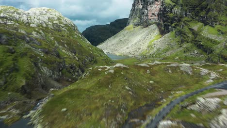 a narrow mountain road follows the river through the norwegian roldalsfjellet valley