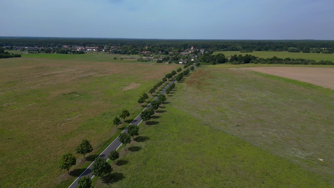 countryside landscape with a road, trees, and cultivated fields. Stunning aerial view flight fly reverse drone