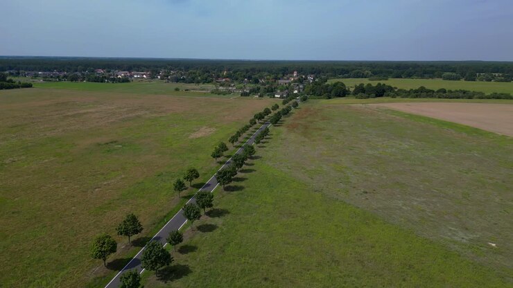 countryside landscape with a road, trees, and cultivated fields. Stunning aerial view flight fly reverse drone