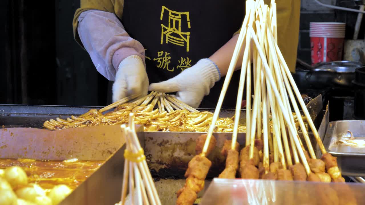 persona de comida callejera cocinando kebabs de calamar con guantes y delantal en chengdu, china