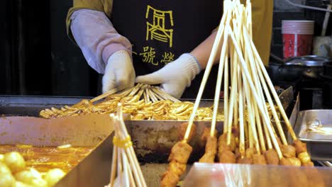 Persona-De-Comida-Callejera-Cocinando-Kebabs-De-Calamar-Con-Guantes-Y-Delantal-En-Chengdu,-China