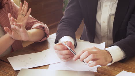 young professional woman explaining something to her colleagues while sitting at table during a team meeting 1