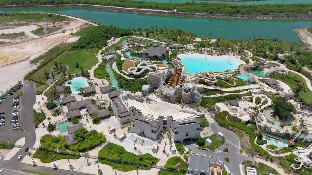 Aerial top down of large El Dorado Water Park with river and parking cars in summer. Chute, swimming pool and luxury Buildings in fun park of Dominican Republic.