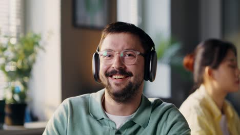 man wearing headphones and smiling in an office environment