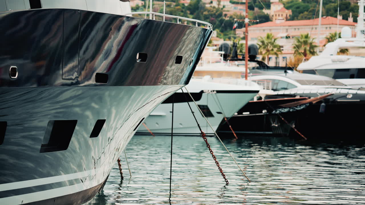 Close up of a yacht's metallic hull reflecting the surrounding marina and water ripples