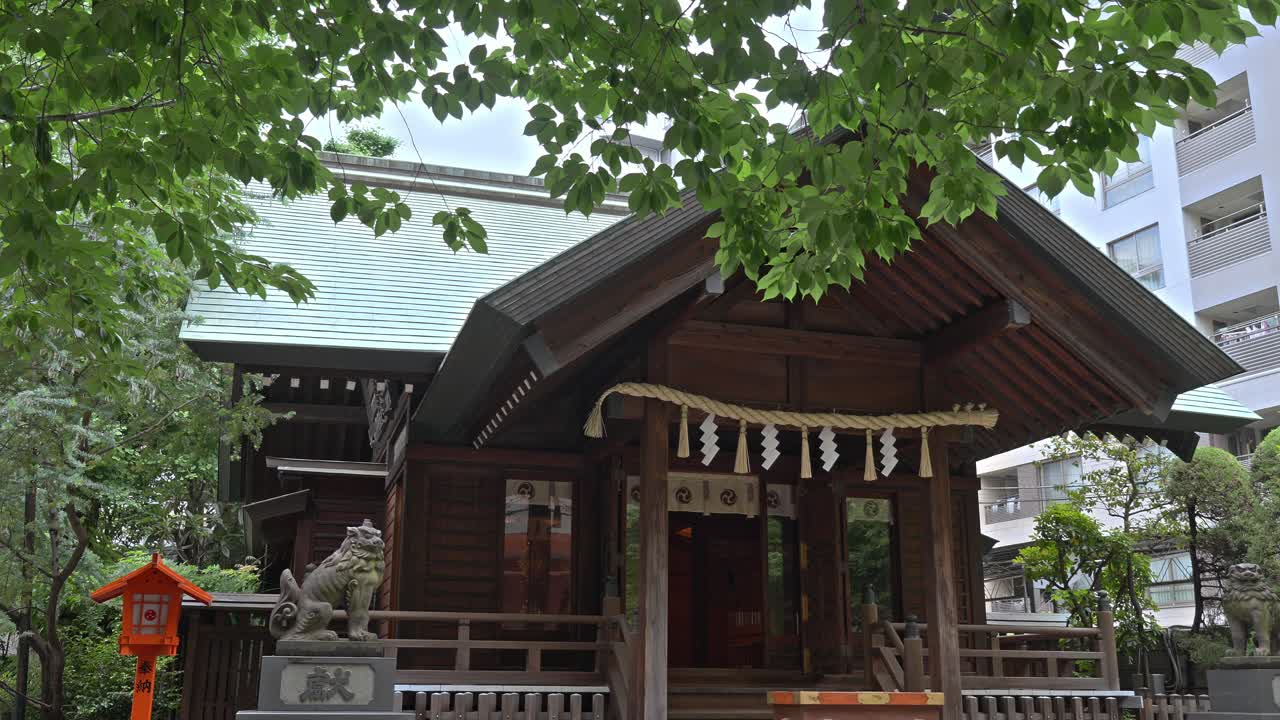 The main hall of Kuramae Shrine with its traditional wooden architecture, nestled amidst lush green foliage, showcasing a serene spiritual atmosphere.