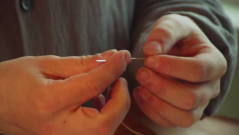 the hands of an experienced tailor thread a tailor's needle to make a bag made of genuine leather