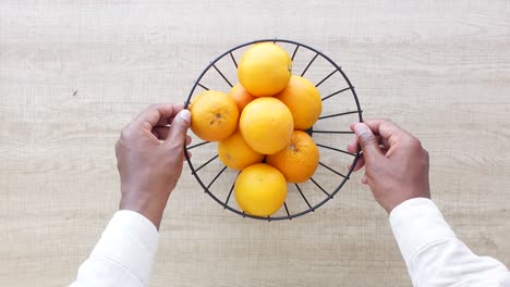 hands holding a bowl of oranges