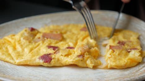 persona comiendo tocino y tortilla de huevo