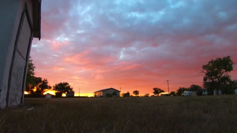 timelapse - gruesas nubes rojas y azules moviéndose sobre la cabeza de un patio en un pequeño pueblo al lado de un viejo hospital abandonado cerca de alberta canada filmado durante el atardecer