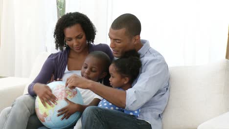 una joven familia afroamericana con un globo terrestre