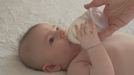 newborn baby feeding on milk bottle, mother bonding holding time white bedroom