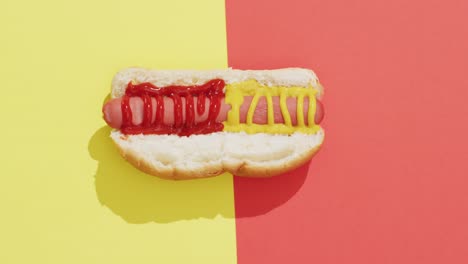 Video-of-hot-dog-with-mustard-and-ketchup-on-a-yellow-and-red-surface