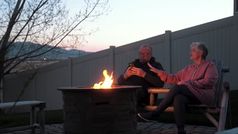 senior husband ignores wife until she demands he put down his smartphone by the fire pit