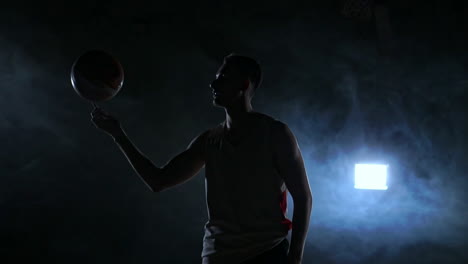 basketball player performing different tricks and spinning ball in dark gym with smoke. slow motion