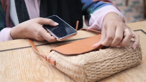 woman using a phone with a handbag