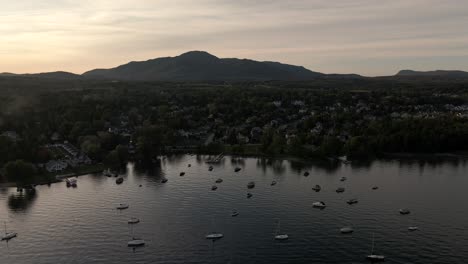 sailboats moored over the calm beach water in lake memphremagog, quebec, canada on a sunset - aerial drone