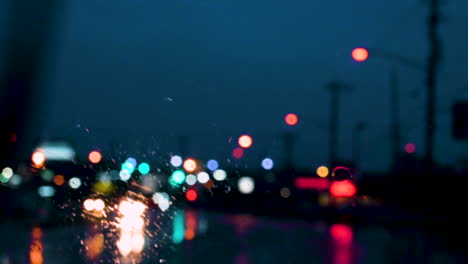 colourful bokeh street lights and car wiper rain drops on the window