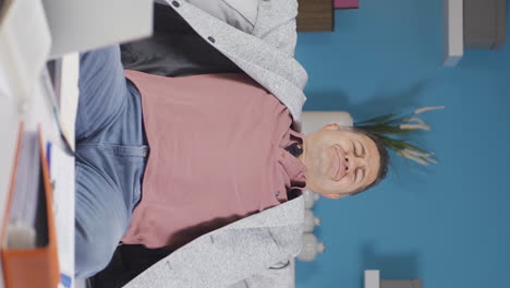 vertical video of home office worker old man yawns and relaxes at the camera.