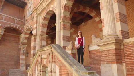 woman stands on the steps at loggia in hotel d'assezat, french renaissance hotel in toulouse, france. - wide shot