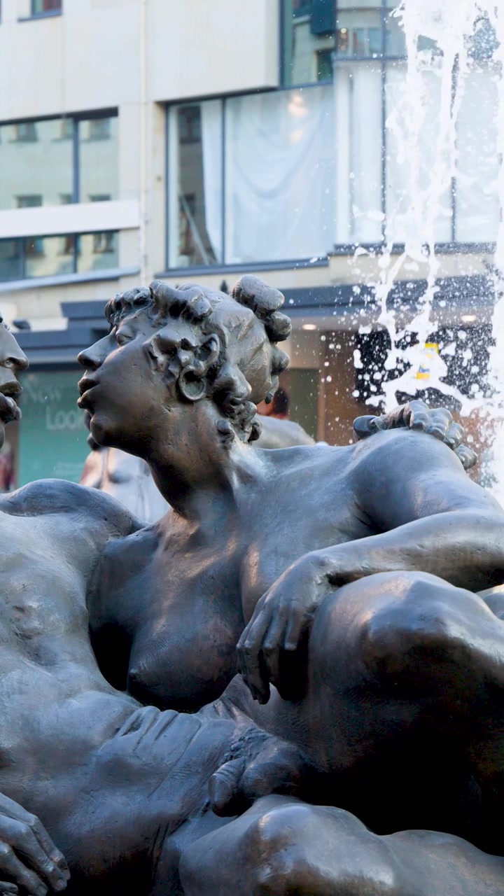 Statua dettagliata in bronzo di figure maschili e femminili in una fontana urbana
