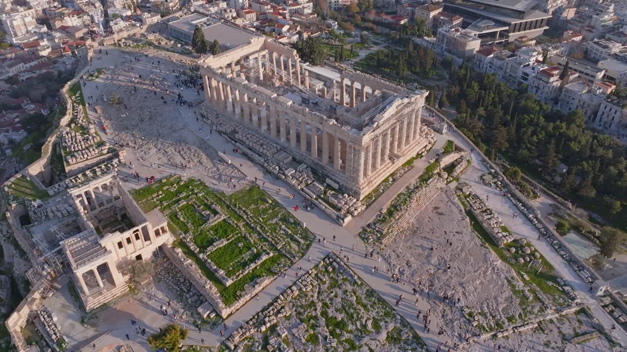 Drone-kuvaus Erechtheionista kohti Parthenonia Ateenan Akropoliilla, Kreikassa. Muinaisissa raunioissa kävelevät turistit luovat vilkkaan historiallisen kohtauksen, joka on ihanteellinen matkailuun ja kulttuuriin