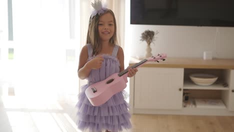 a beautiful little girl is playing the ukulele in the living room for her mom.