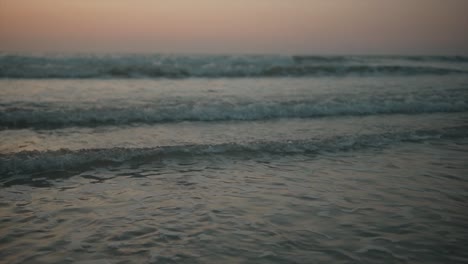 Kleine-Schäumende-Wellen,-Die-Ruhig-über-Das-Ufer-Rollen-Und-Im-Morgengrauen-über-Den-Sand-Spülen
