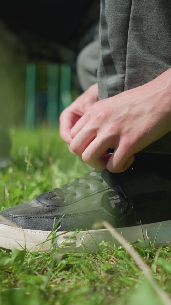 흐릿한 배경으로 잔디에 앉아 있는 세 사람이 신발을 조정하는 클로즈업 다리 시각