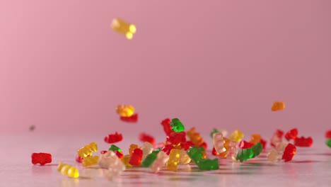 gummy bears fall in slow motion onto surface in front of pink background