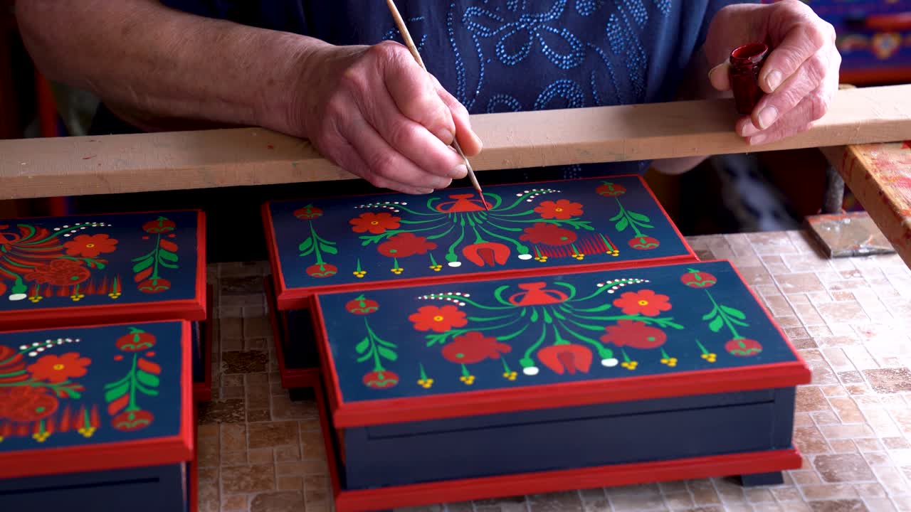 Artisan painting traditional Matyó floral patterns on decorative wooden box