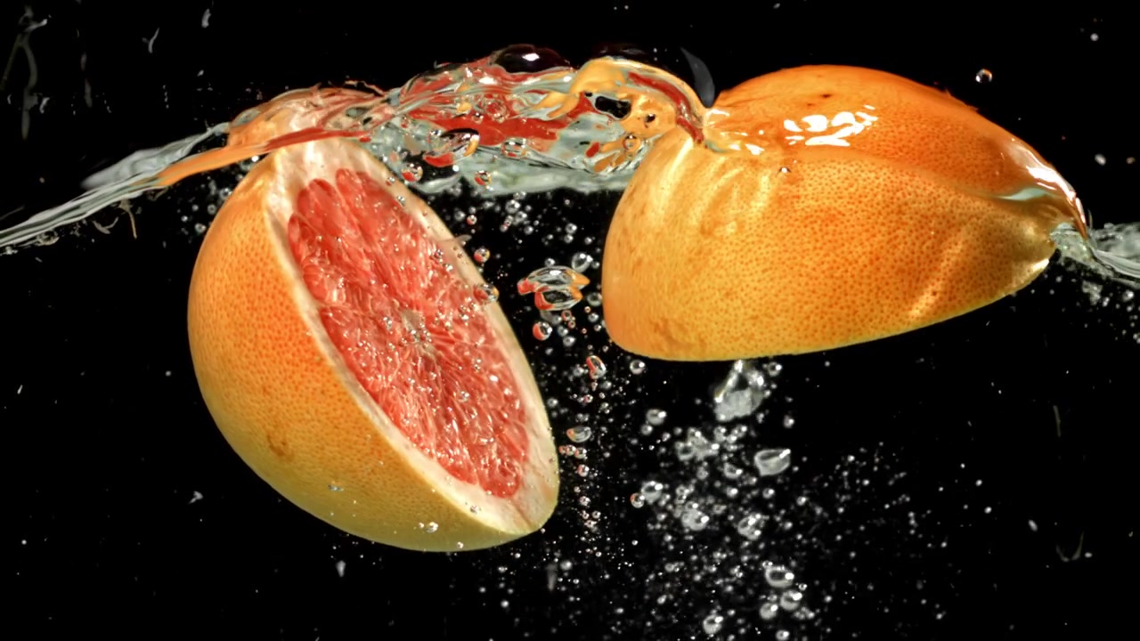 Metà di pompelmo fresco che schizzano nell'acqua con bolle