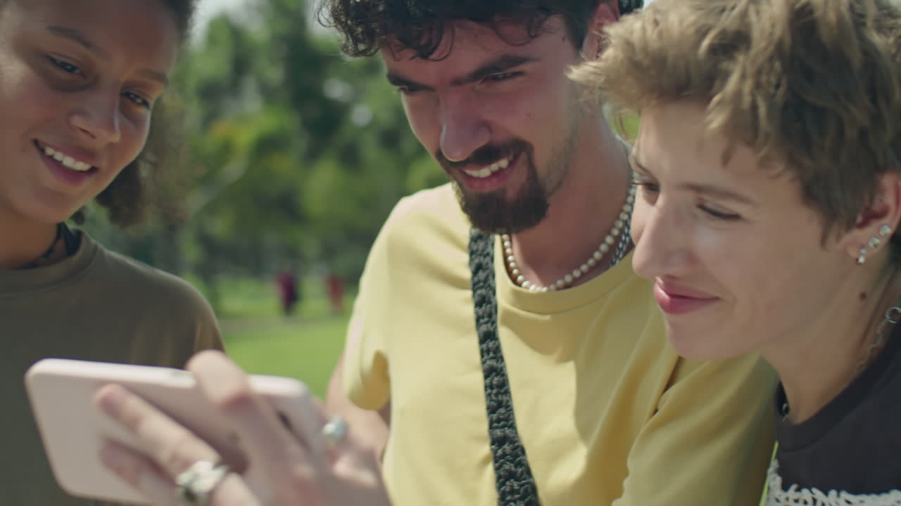 Cheerful Friends Using Smartphone and Chatting Outdoors