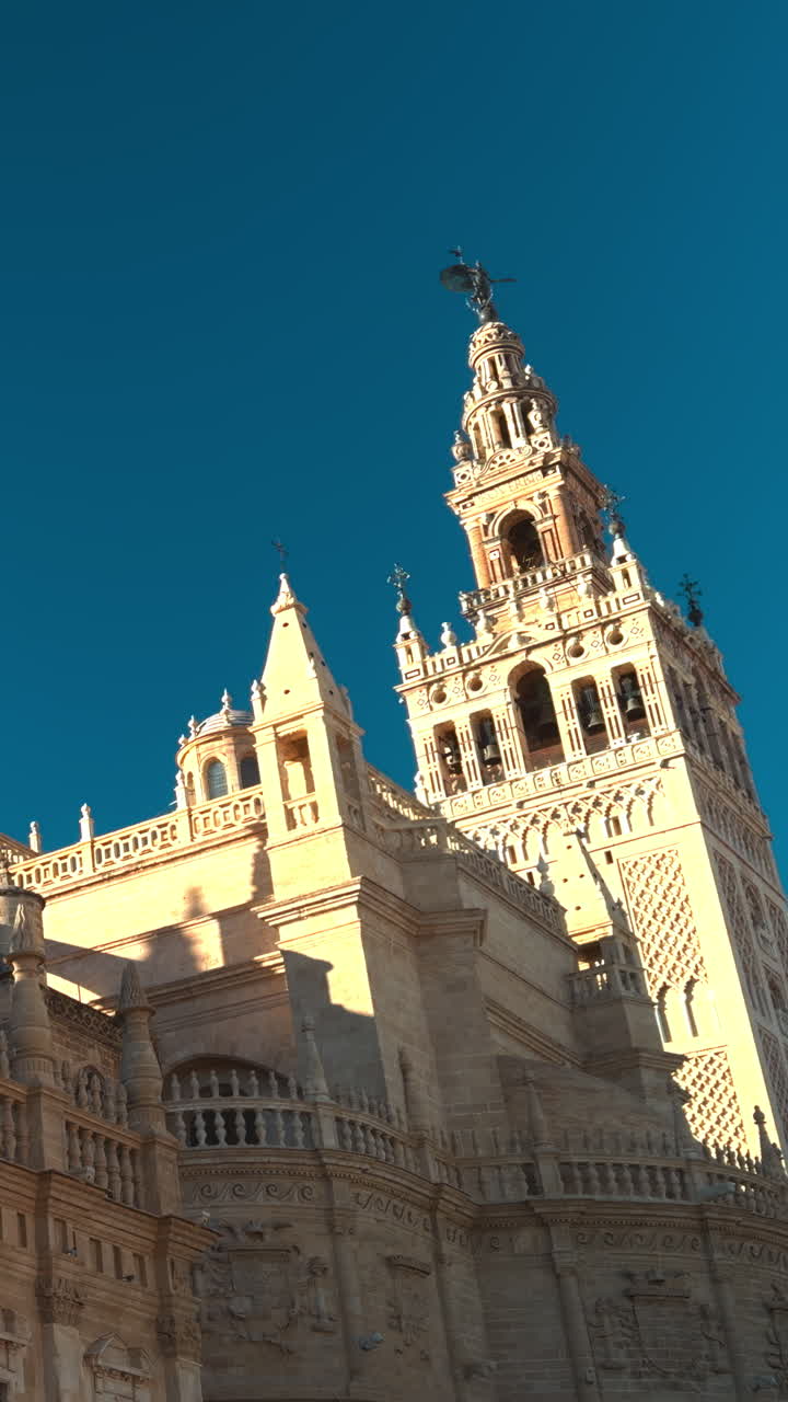 Facciata di cattedrale illuminata dal sole con torre imponente, panoramica cinematografica con drone all'ora d'oro cattura guglie ornate e pietra.