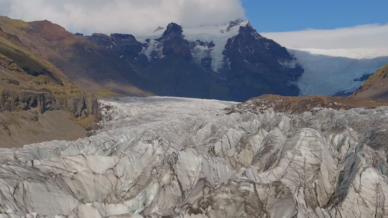Un enorme ghiacciaio islandese, che mette in mostra crepacci blu ghiaccio, cime innevate e un terreno circostante aspro. Una vista spettacolare della natura selvaggia e ghiacciata dell'Islanda.