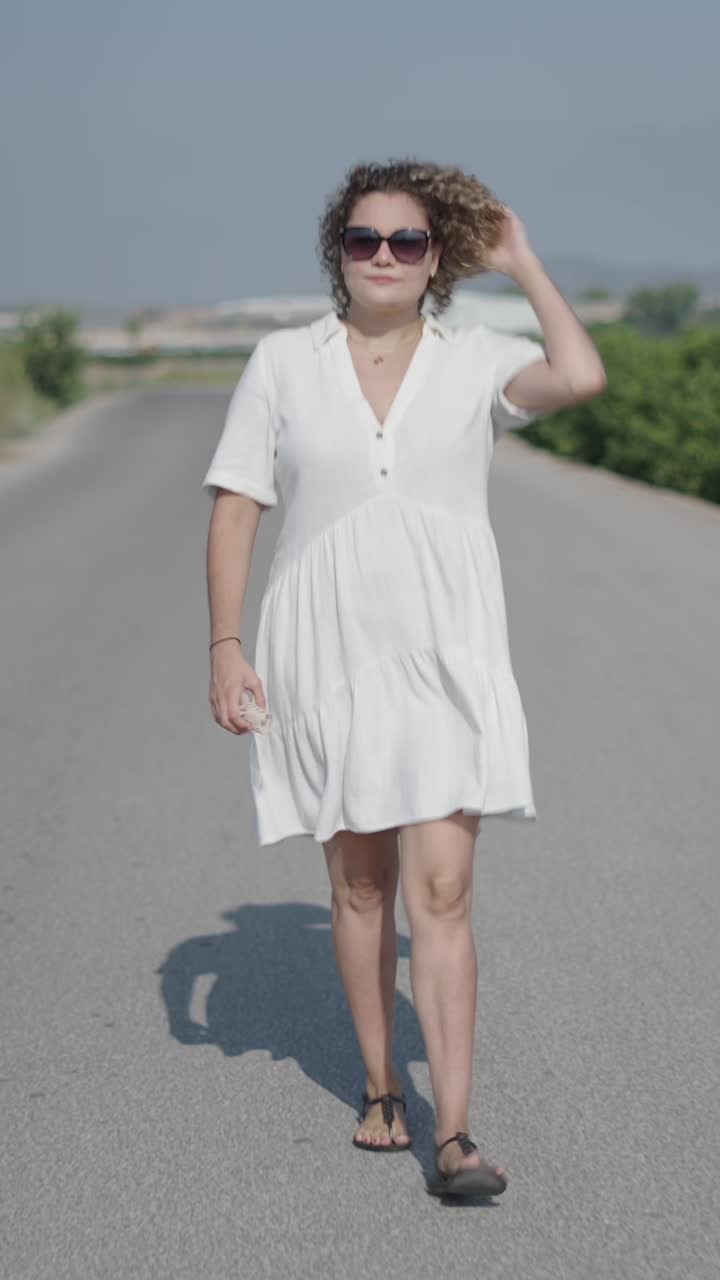 Woman in a white dress walking on a road